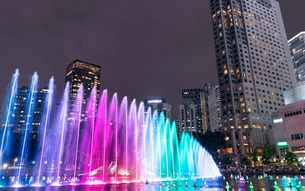Colorful Symphony Water Fountain Show in Kuala Lumpur with city skyline at night.