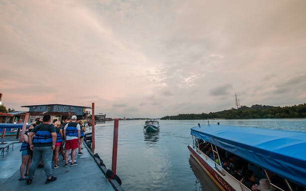 Tourists boarding a boat at sunset for the Kuala Selangor Fireflies Night Tour.