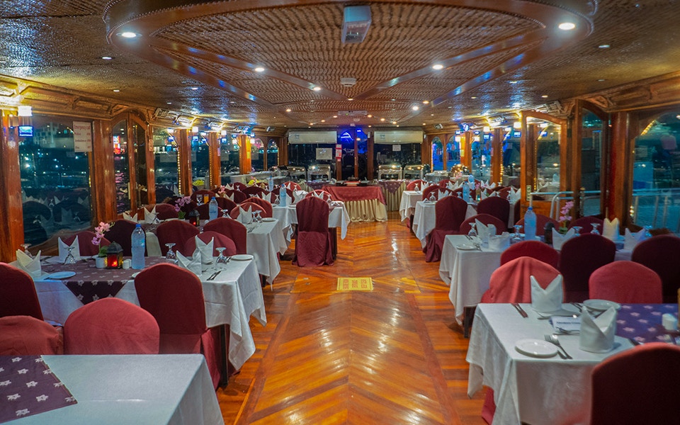 Dhow sailing on Dubai Creek with guests enjoying dinner and live entertainment.