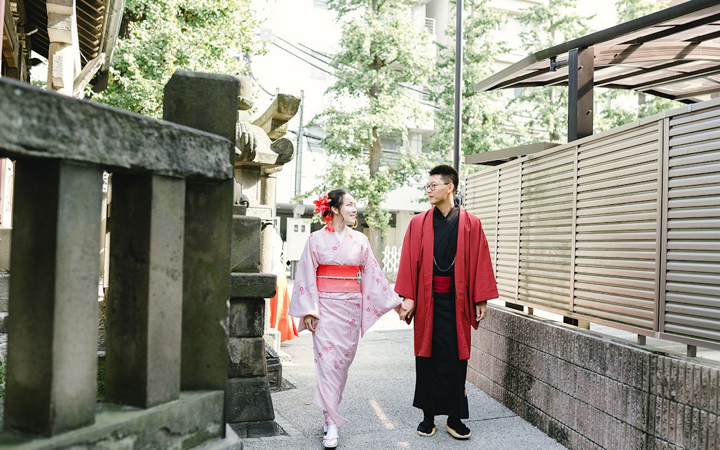 Couple in traditional kimonos walking in a Tokyo temple garden.