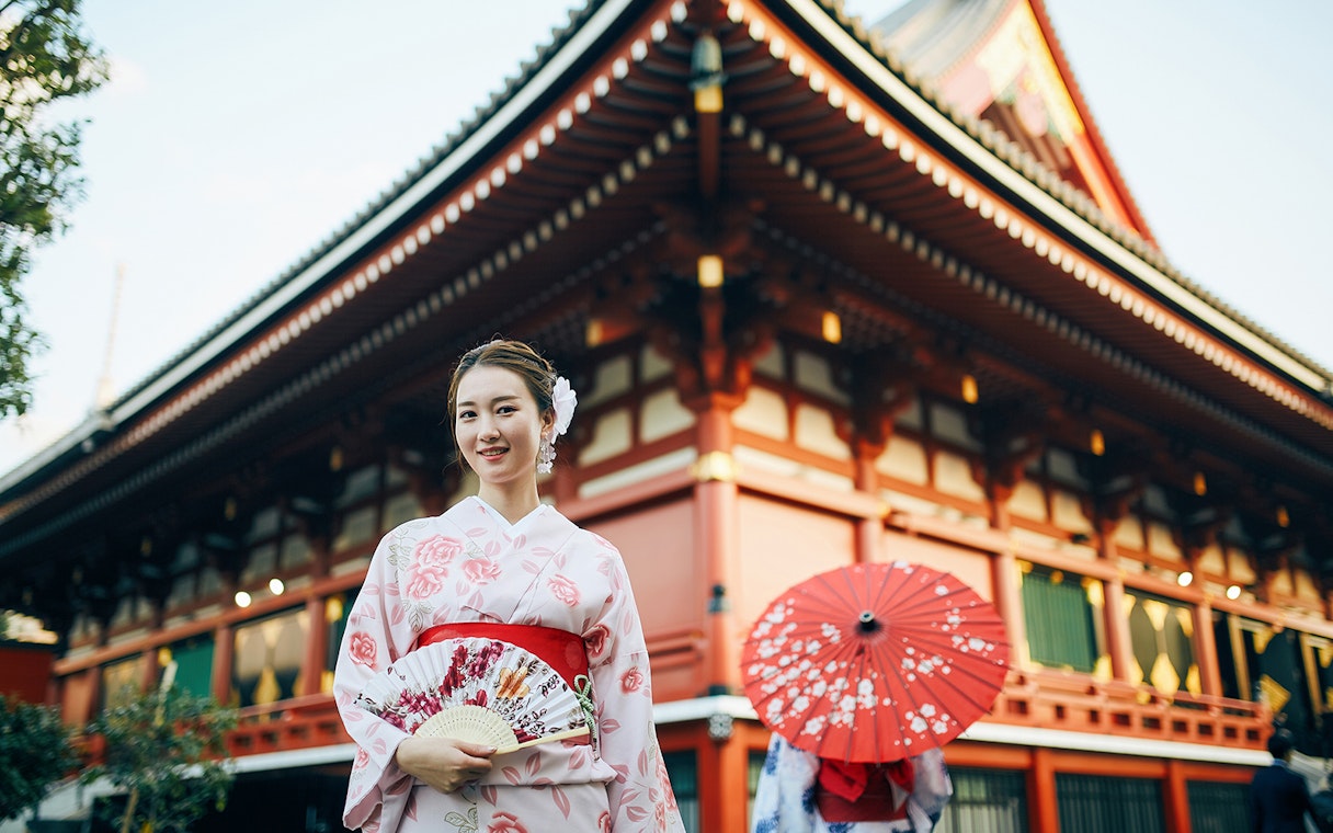 Person in kimono holding a fan in front of Senso-ji Temple, Tokyo.