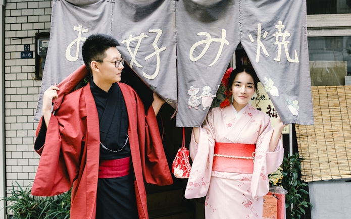 Two people in traditional kimonos at a Tokyo entrance curtain.