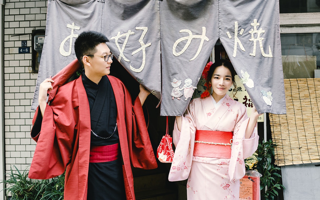 Two people in traditional kimonos at a Tokyo entrance curtain.
