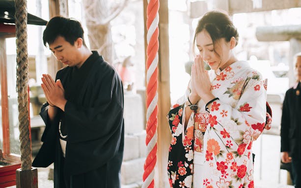 People in traditional kimonos praying at a Tokyo shrine.