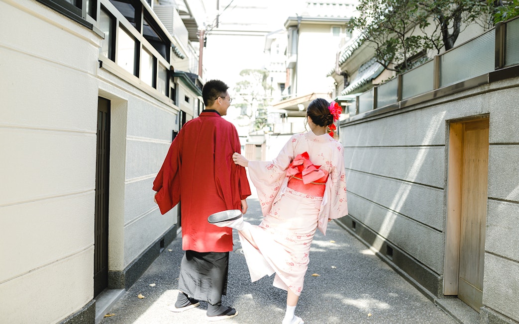 Couple walking in traditional kimonos through a narrow street in Tokyo.