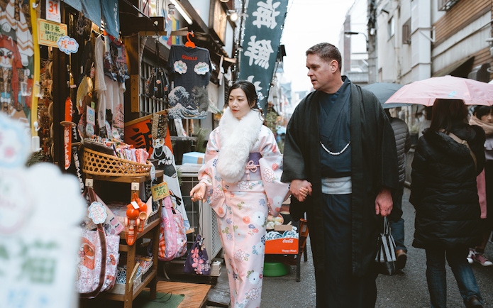Couple in traditional kimonos walking through a Tokyo market street.