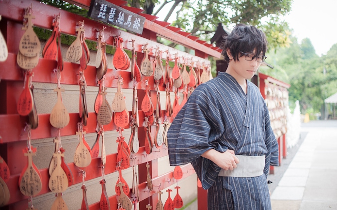 Person in kimono standing by ema prayer plaques in Tokyo.