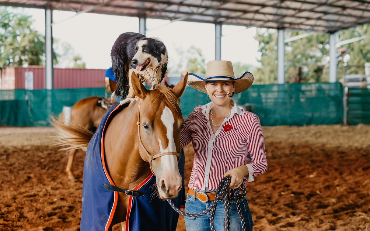 Horse and dog performing with a smiling woman at Katherine Outback Experience show.