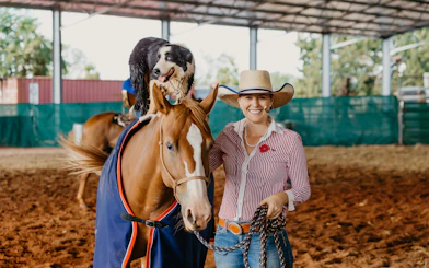 Horse and dog performing with a smiling woman at Katherine Outback Experience show.