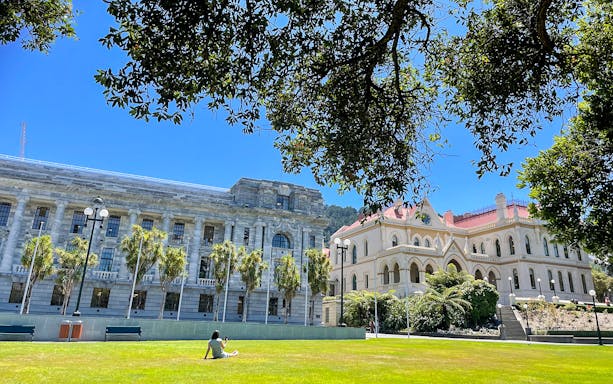 Wellington Parliament Buildings with person relaxing on lawn, New Zealand.