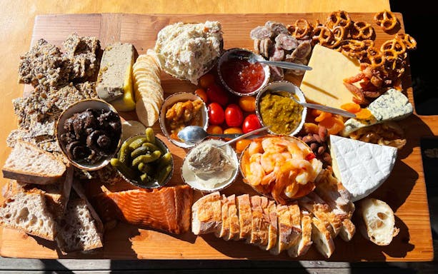 Charcuterie board with assorted cheeses, meats, bread, and condiments for A Taste of Martinborough – Wine Delights Tour.