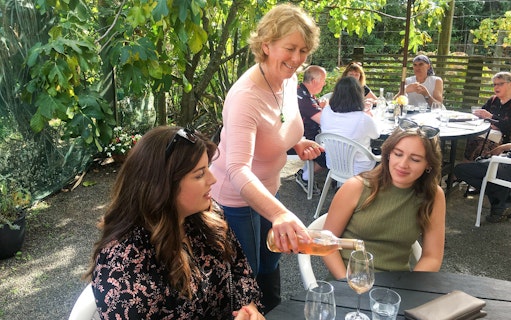Pouring wine for guests at an outdoor table on the Martinborough Wine Delights Tour.
