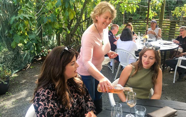 Pouring wine for guests at an outdoor table on the Martinborough Wine Delights Tour.