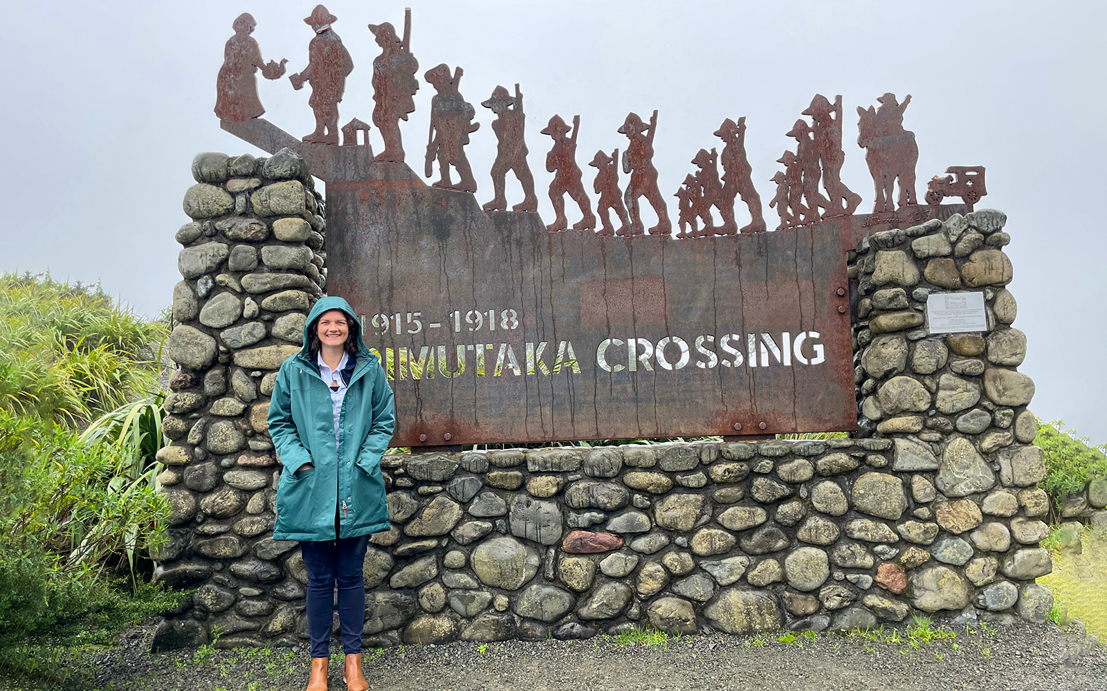 Person standing by the Rimutaka Crossing sign, South Wairarapa tour.
