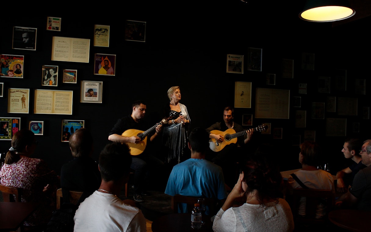 Fado musicians performing at Ideal Clube with audience seated.