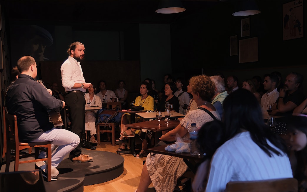 Fado singer performing at Ideal Clube with audience seated around tables.
