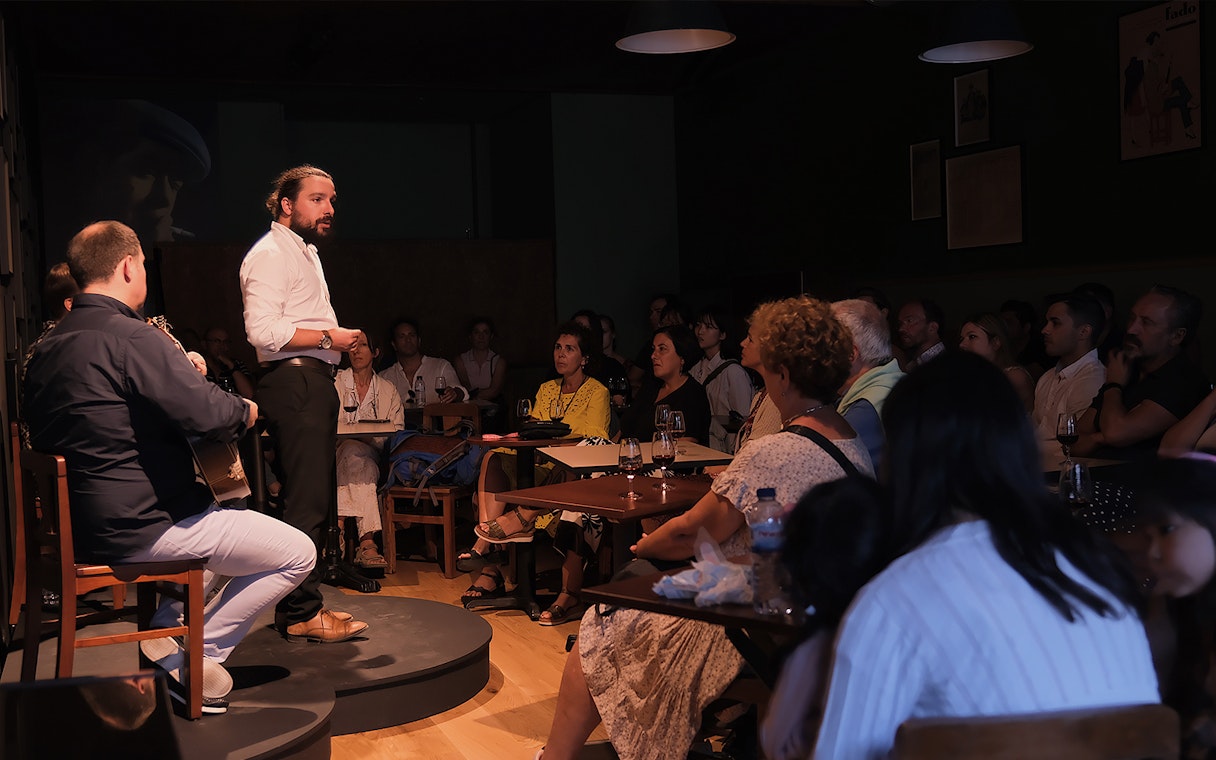 Fado singer performing at Ideal Clube with audience seated around tables.