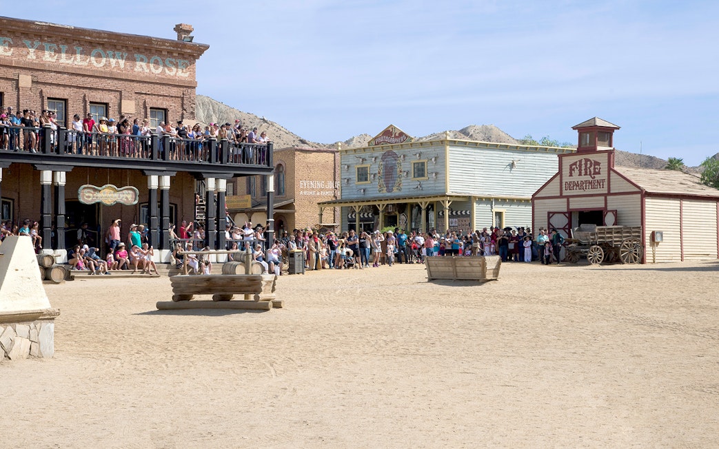 Crowd at Oasys MiniHollywood's Western town, Almería, with historic buildings and wagon.