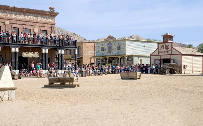 Crowd at Oasys MiniHollywood's Western town, Almería, with historic buildings and wagon.