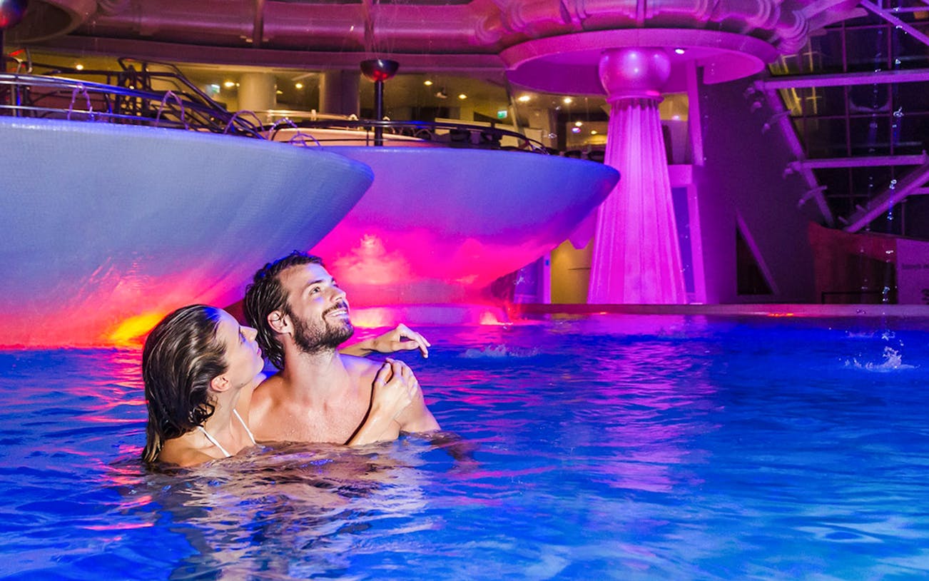 Couple enjoying the illuminated pool at Thermoludic, Caldea.