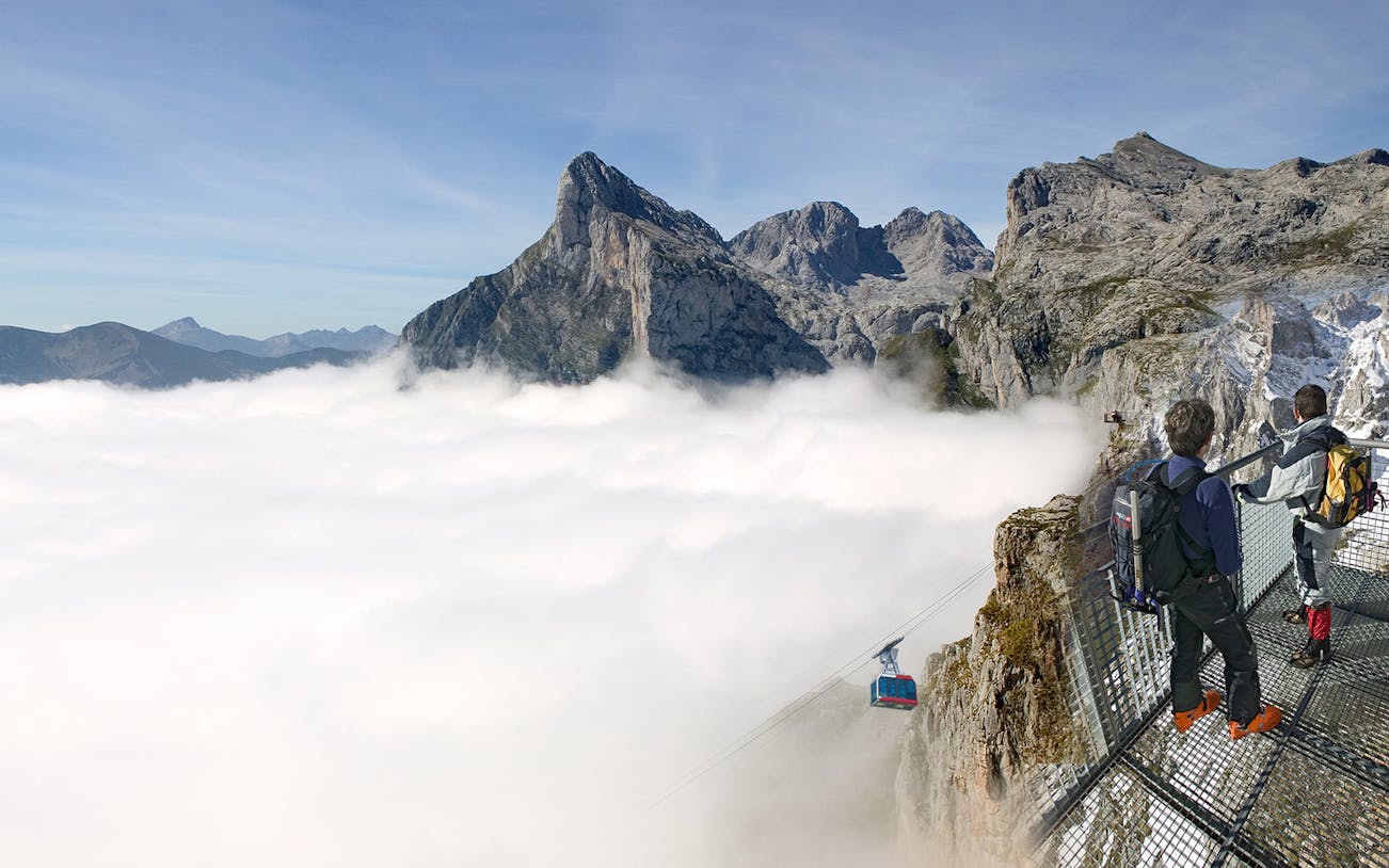 Visitors on a viewing platform overlooking the Fuente Dé Cable Car and Picos de Europa mountains.