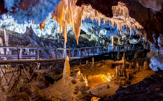 Walkway through stalactites and stalagmites in El Soplao Cave during guided tour.