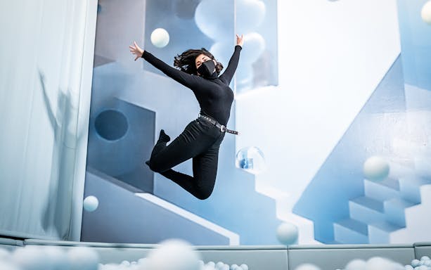 Person jumping in a room with geometric art at Ikono in Madrid.
