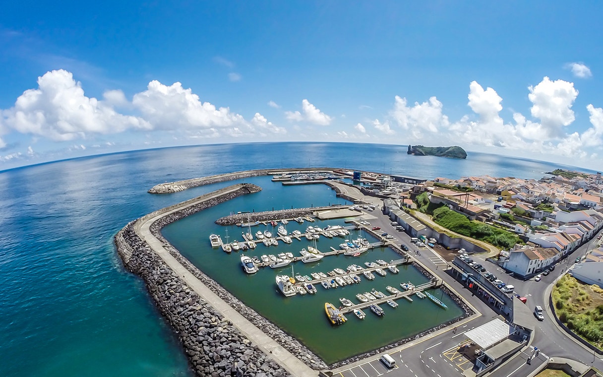 Marina with boats at Azores Islands, ocean view, and distant islet.