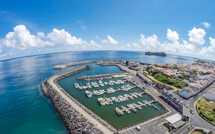 Marina with boats at Azores Islands, ocean view, and distant islet.