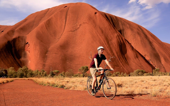 Cyclist riding near Uluru in Australia with audio guide.