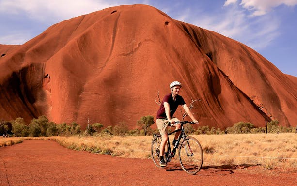 Cyclist riding near Uluru in Australia with audio guide.