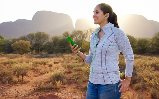Person using audio guide at Uluru with rock formations in the background.
