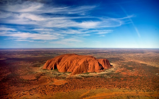 Aerial view of Uluru in Australia with surrounding desert landscape.