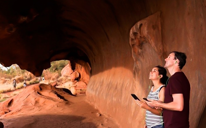 Visitors using audio guides at Uluru rock formation, Australia.