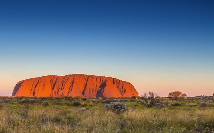 Uluru at sunset with surrounding landscape, Australia, for audio guide tour.