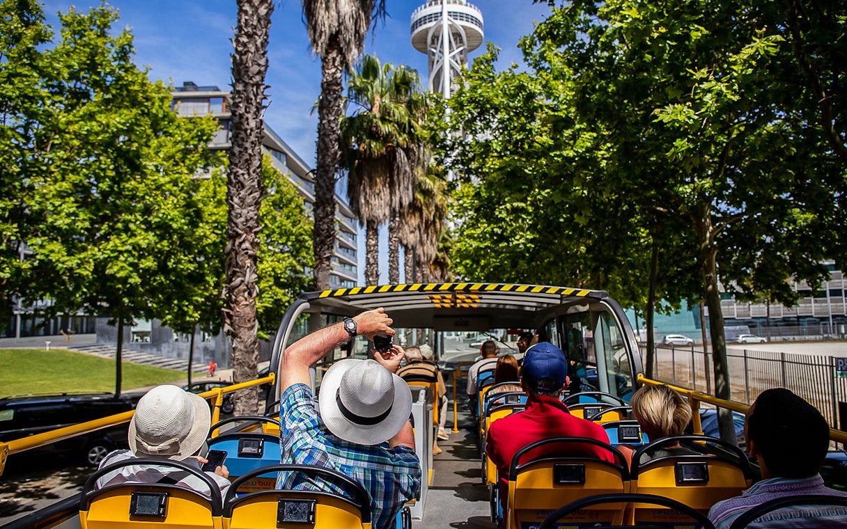 Open-top bus tour in Lisbon with tourists viewing city landmarks.