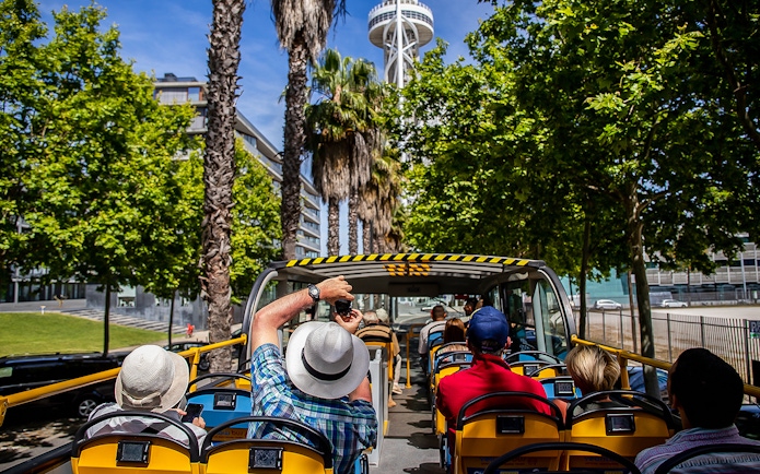 Open-top bus tour in Lisbon with tourists viewing city landmarks.