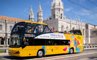 Yellow hop-on hop-off bus in front of Jerónimos Monastery, Lisbon.