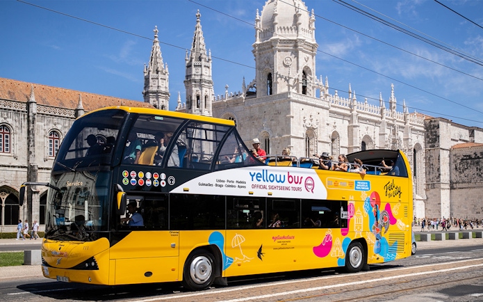 Yellow hop-on hop-off bus in front of Jerónimos Monastery, Lisbon.