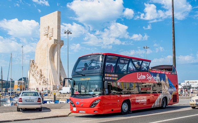 Lisbon sightseeing bus near Padrão dos Descobrimentos monument.