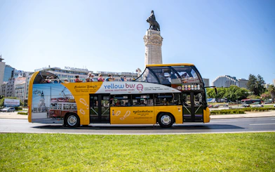 Lisbon hop-on hop-off bus passing Marquês de Pombal statue.