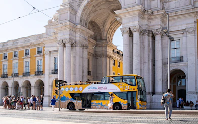 Lisbon hop-on hop-off bus near Arco da Rua Augusta with tourists boarding.