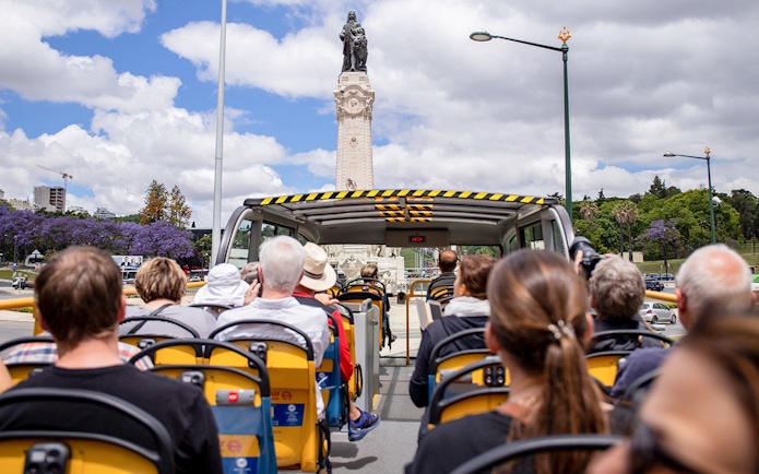 Lisbon hop-on hop-off bus approaching Marquis of Pombal Square statue.
