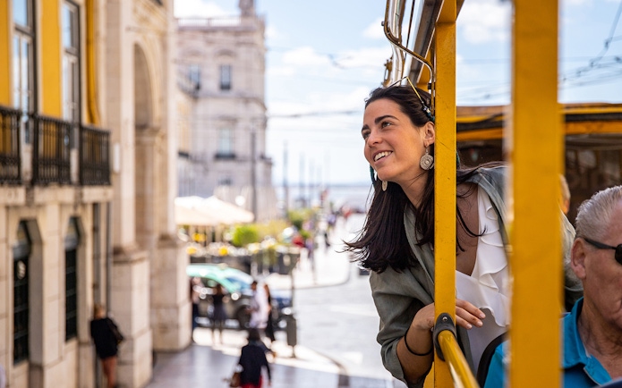 Woman enjoying view from Lisbon tram during hop-on hop-off bus tour.