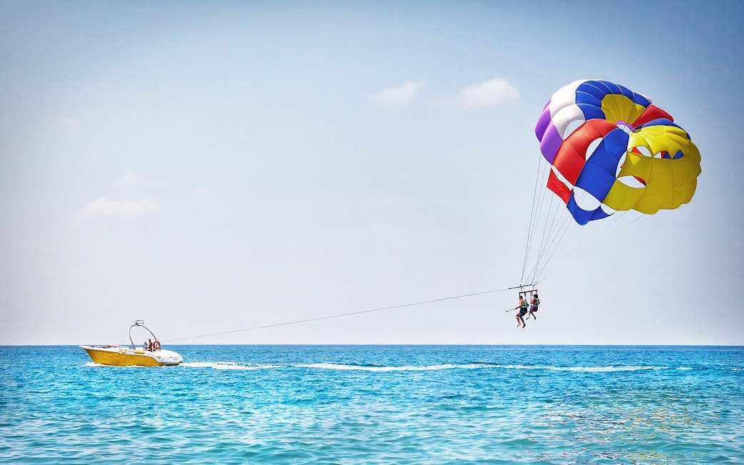 Parasailing over the ocean in Pantai Cenang with colorful parachute and speedboat.
