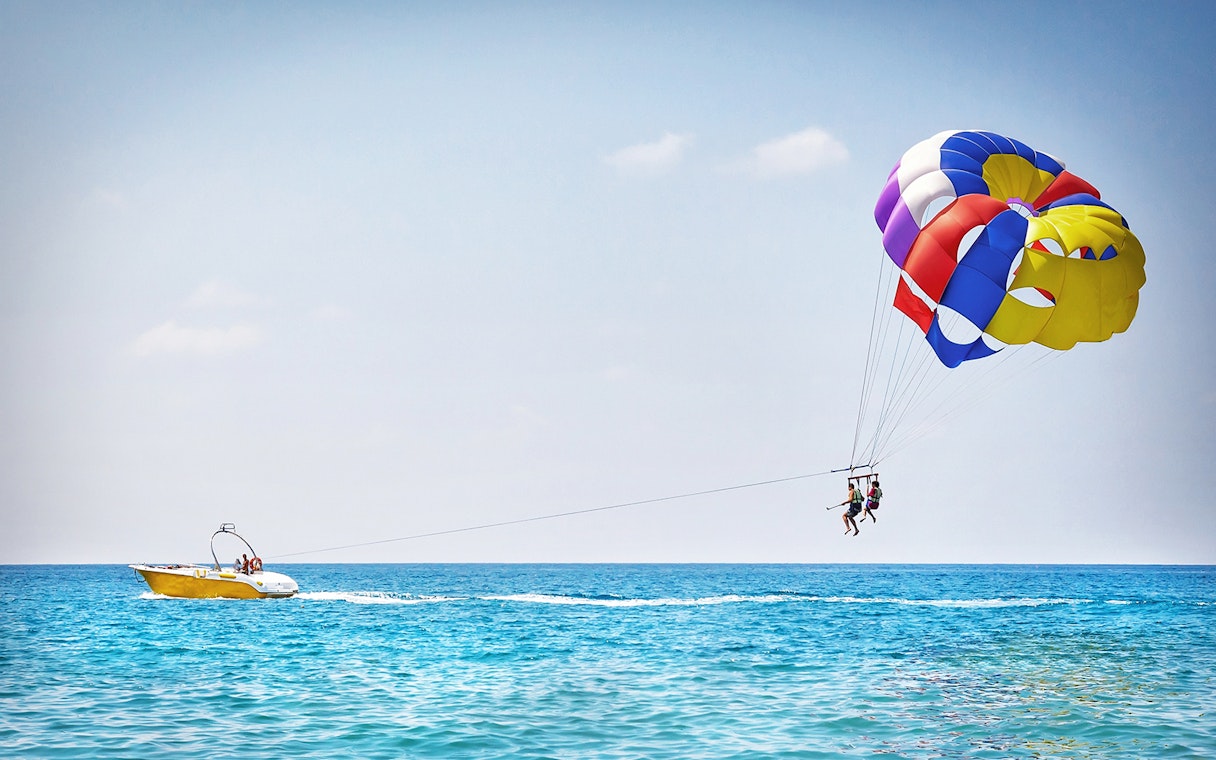 Parasailing over the ocean in Pantai Cenang with colorful parachute and speedboat.