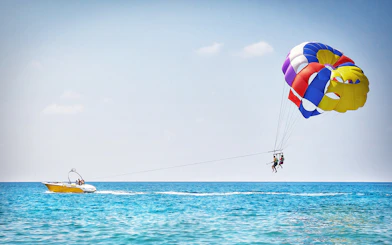 Parasailing over the ocean in Pantai Cenang with colorful parachute and speedboat.