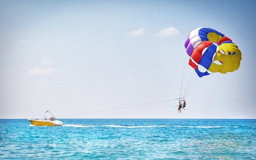 Parasailing over the ocean in Pantai Cenang with colorful parachute and speedboat.