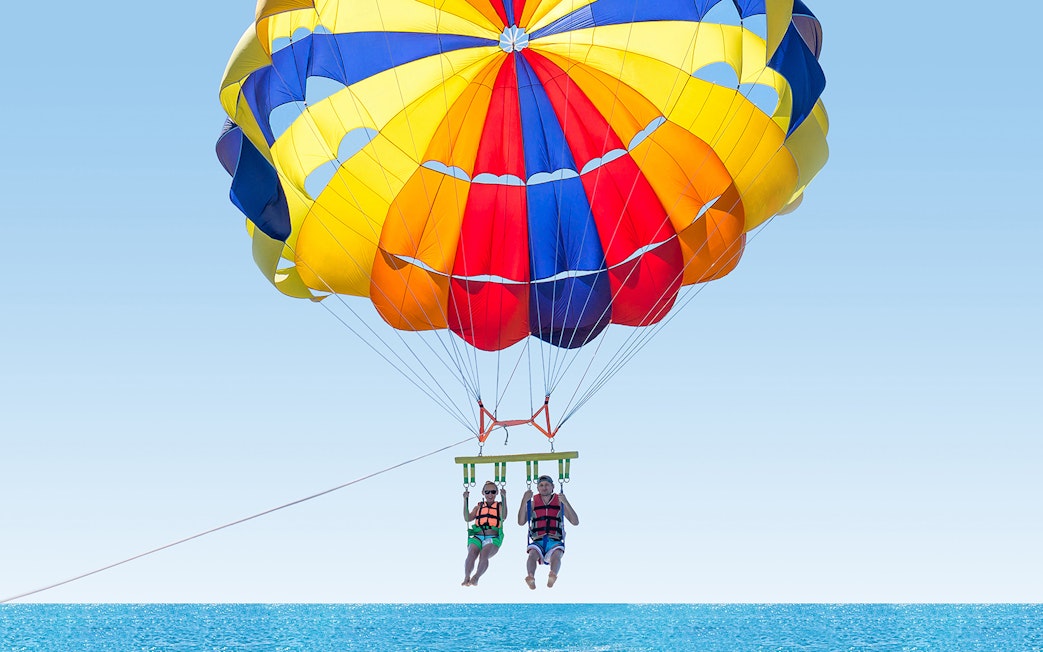 Parasailing over the ocean in Pantai Cenang with colorful parachute.