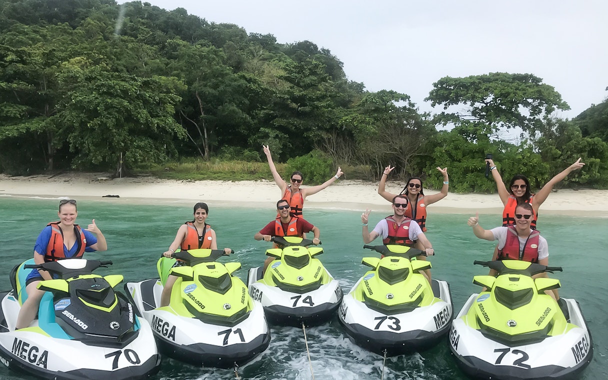 Group enjoying jet ski ride near Langkawi beach with lush greenery in the background.